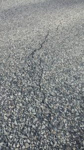 Asphalt driveway with a crack running lengthwise down the middle