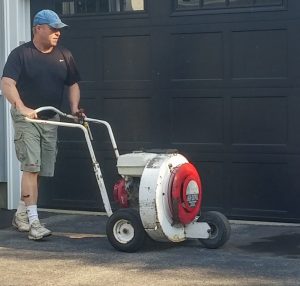 Steve Cametti pushing a commercial blower across the asphalt driveway
